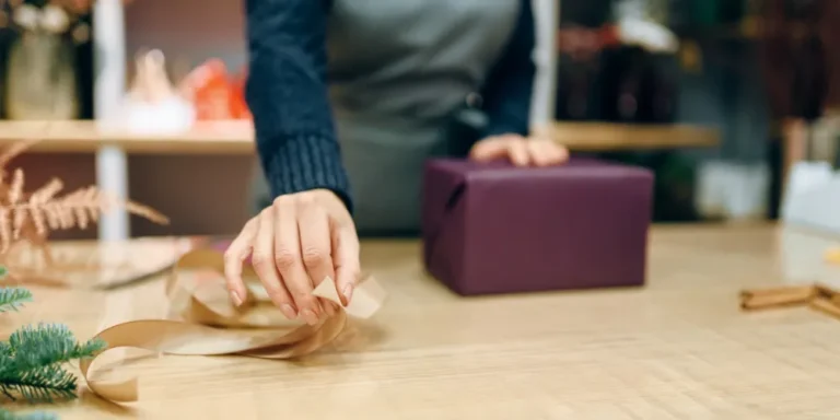Mani che incartano un regalo con carta e nastro