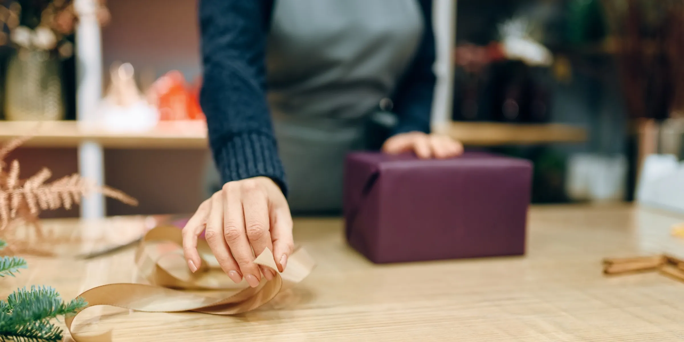 Mani che incartano un regalo con carta e nastro